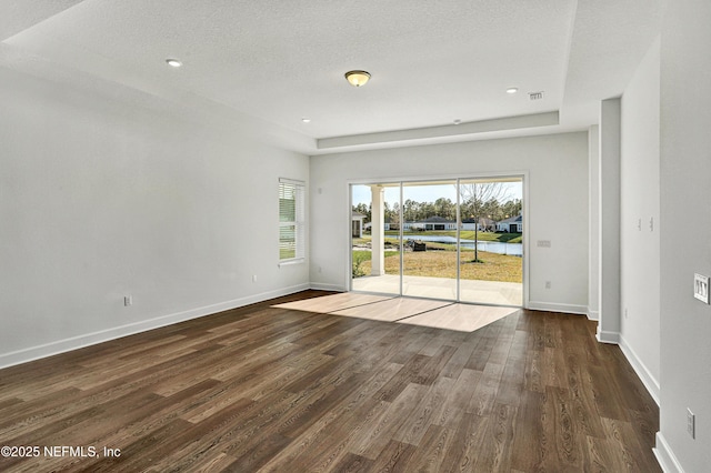 unfurnished room with dark wood-style flooring, a textured ceiling, and baseboards