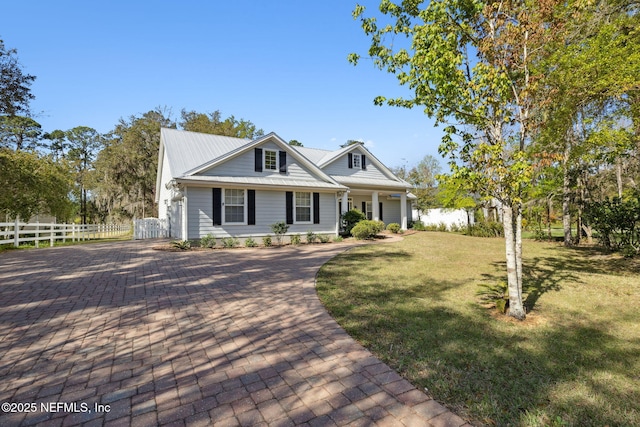 view of front facade featuring fence, metal roof, decorative driveway, and a front yard