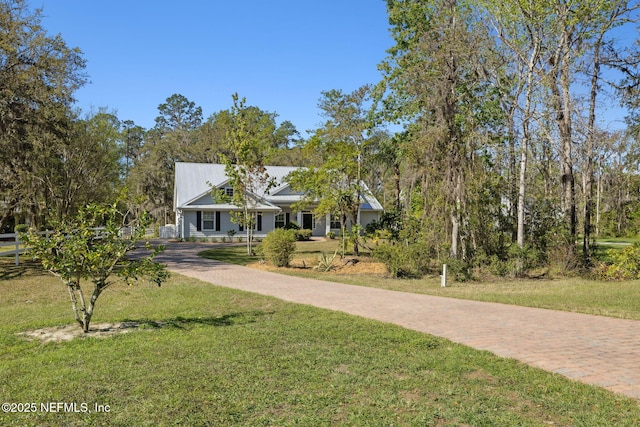 view of front facade with metal roof, a front lawn, and decorative driveway