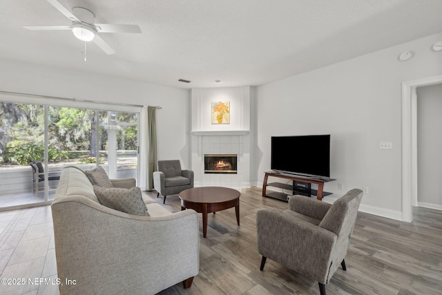 living room featuring visible vents, baseboards, a ceiling fan, wood finished floors, and a fireplace