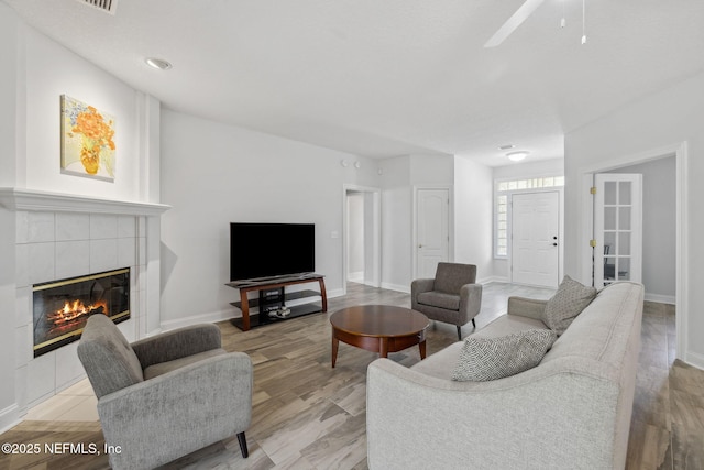 living area featuring a fireplace, light wood-style flooring, and baseboards