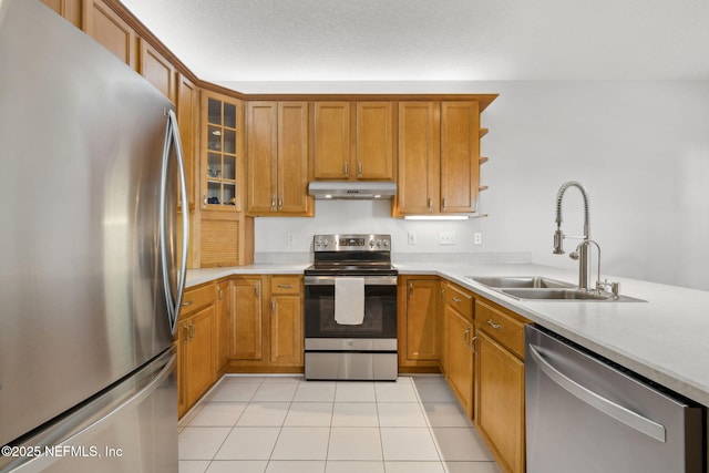 kitchen featuring light tile patterned floors, under cabinet range hood, stainless steel appliances, a sink, and light countertops