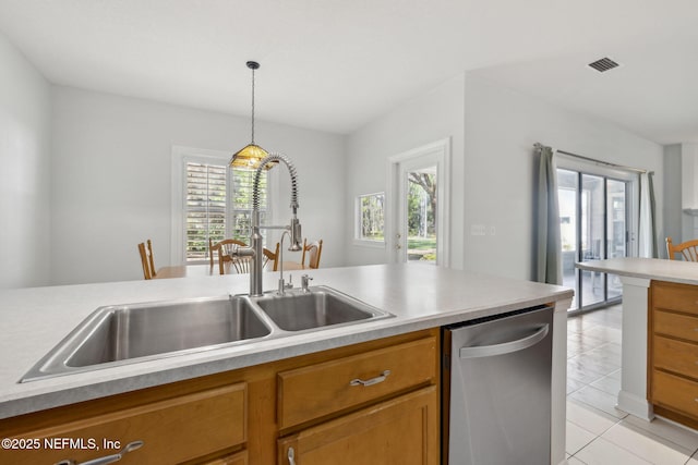 kitchen featuring visible vents, brown cabinetry, dishwasher, decorative light fixtures, and a sink