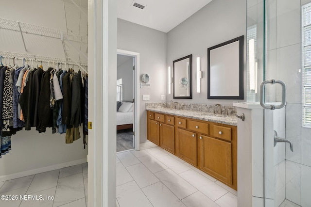 full bath featuring double vanity, a stall shower, visible vents, a spacious closet, and a sink