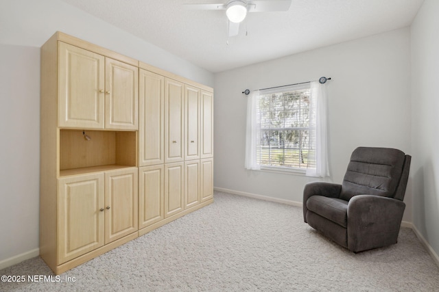 living area with light carpet, ceiling fan, and baseboards