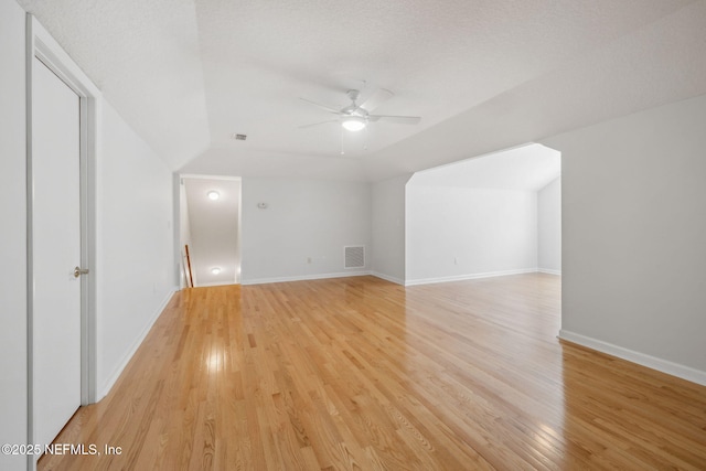 additional living space with ceiling fan, a textured ceiling, light wood-style flooring, visible vents, and baseboards