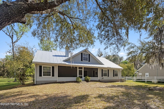 view of front of house featuring a front yard, metal roof, a chimney, and fence