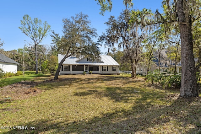 view of front of home featuring metal roof, a front lawn, and fence