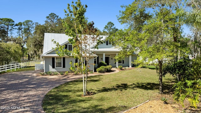 view of front of house with decorative driveway, a porch, a front yard, fence, and metal roof