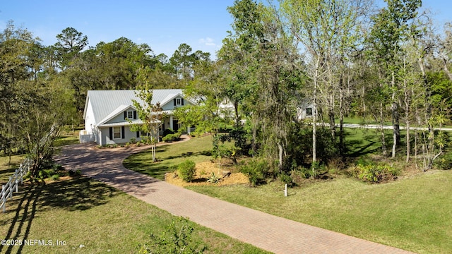 view of front of home with a front yard, decorative driveway, and metal roof