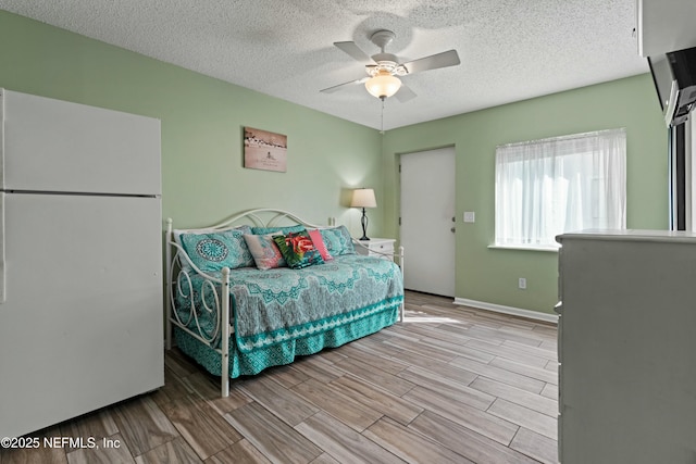 2211 1st St S, Jacksonville Beach, FL 32250 - bedroom with freestanding refrigerator, wood finish floors, a textured ceiling, a ceiling fan, and baseboards