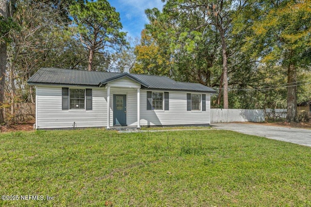 view of front facade with fence, metal roof, and a front yard