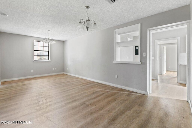 3135 Soutel Dr, Jacksonville, FL 32208 - unfurnished room featuring light wood finished floors, baseboards, a chandelier, and a textured ceiling
