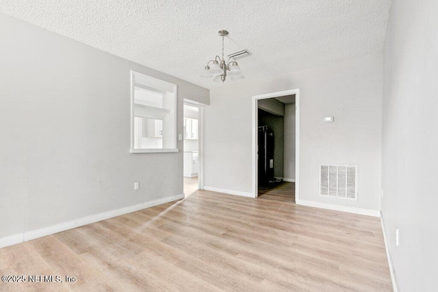 3135 Soutel Dr, Jacksonville, FL 32208 - empty room featuring light wood finished floors, baseboards, visible vents, a textured ceiling, and a notable chandelier