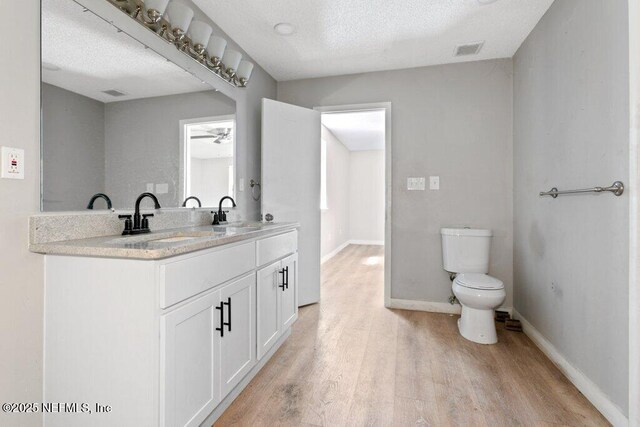 3135 Soutel Dr, Jacksonville, FL 32208 - full bath with toilet, wood finished floors, a sink, visible vents, and baseboards