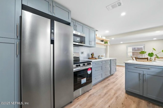 kitchen featuring tasteful backsplash, visible vents, light wood-style flooring, appliances with stainless steel finishes, and light countertops