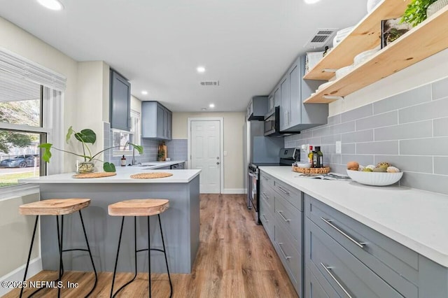 kitchen featuring visible vents, appliances with stainless steel finishes, a breakfast bar, and gray cabinetry