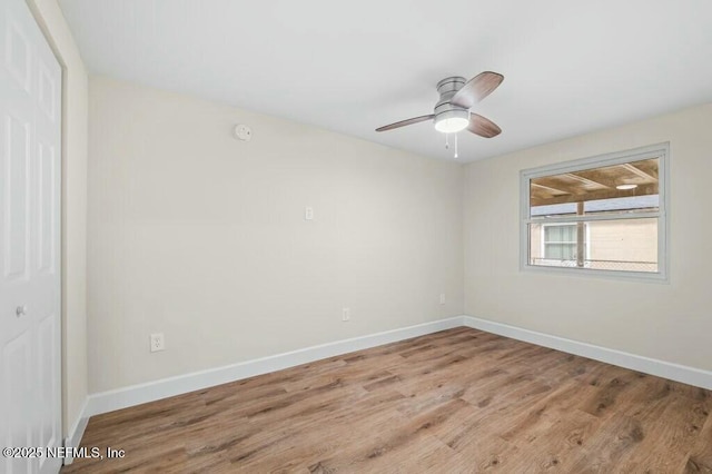 empty room with wood finished floors, a ceiling fan, and baseboards