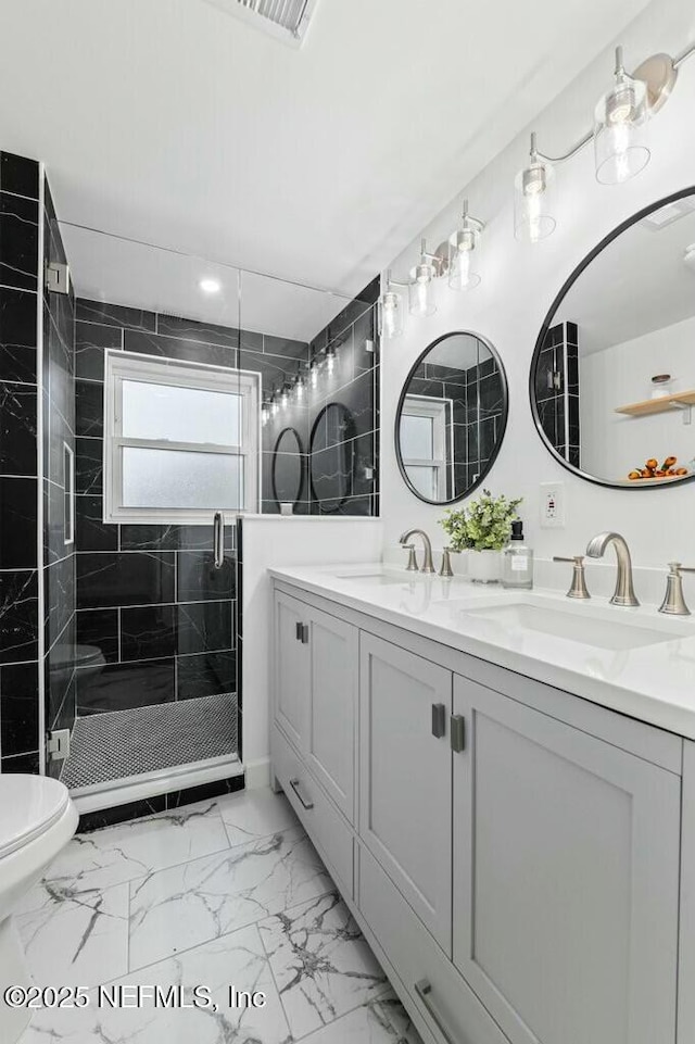 full bath with double vanity, marble finish floor, a shower stall, and a sink