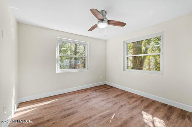 unfurnished room featuring baseboards, wood finished floors, and a healthy amount of sunlight