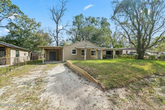 single story home featuring dirt driveway, fence, a front lawn, and a carport