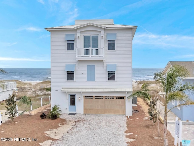 raised beach house featuring a balcony, a water view, a beach view, and metal roof