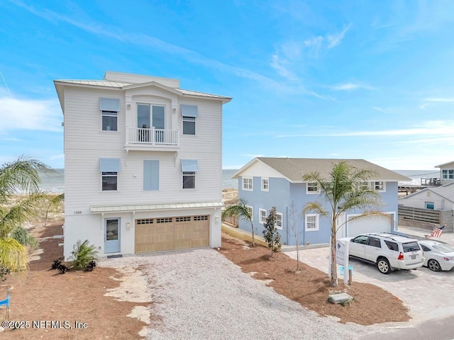 coastal inspired home with a balcony, a standing seam roof, driveway, and metal roof