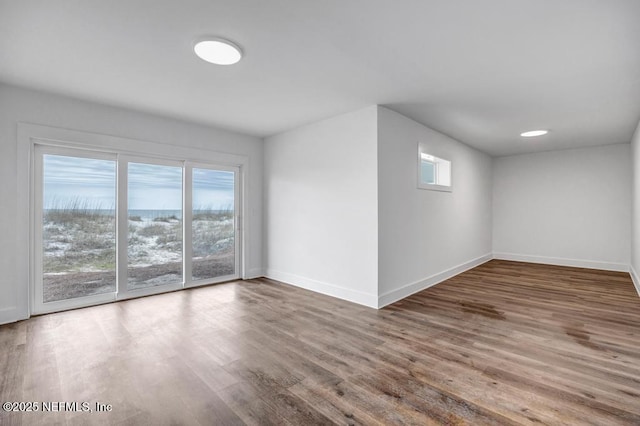 spare room featuring a healthy amount of sunlight, baseboards, and wood finished floors