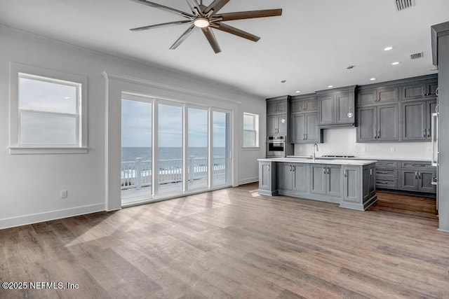 kitchen with light countertops, stainless steel oven, baseboards, and wood finished floors