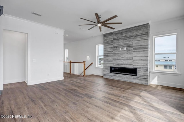 unfurnished living room with ornamental molding, wood finished floors, visible vents, and a healthy amount of sunlight