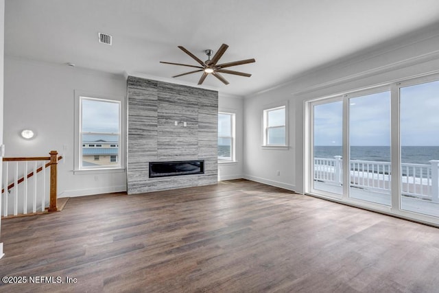 unfurnished living room with crown molding, a fireplace, baseboards, and wood finished floors