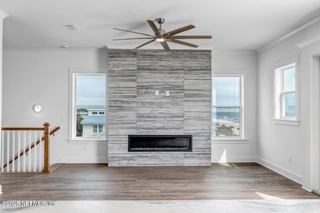 unfurnished living room with a fireplace, ornamental molding, a wealth of natural light, and wood finished floors