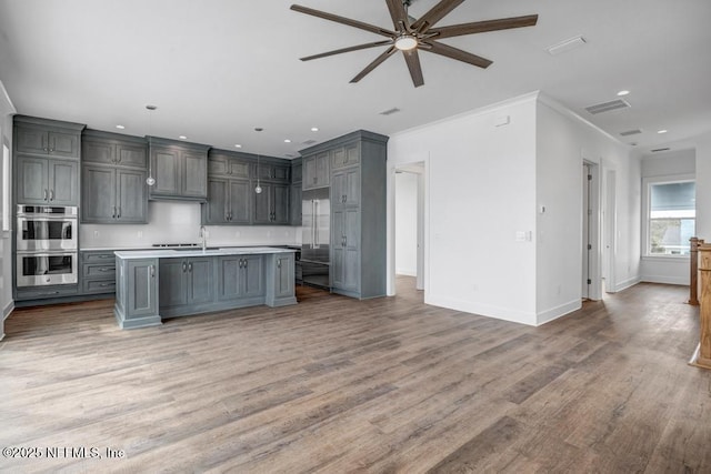 kitchen with visible vents, open floor plan, stainless steel appliances, light countertops, and gray cabinetry