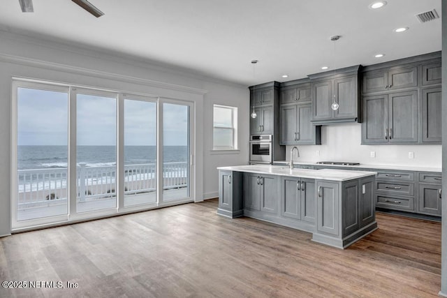 kitchen with gas cooktop, oven, gray cabinetry, a sink, and wood finished floors