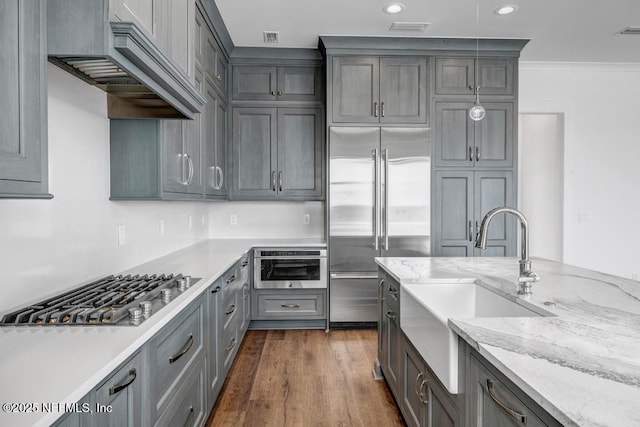 kitchen with dark wood-style flooring, visible vents, ornamental molding, appliances with stainless steel finishes, and custom range hood