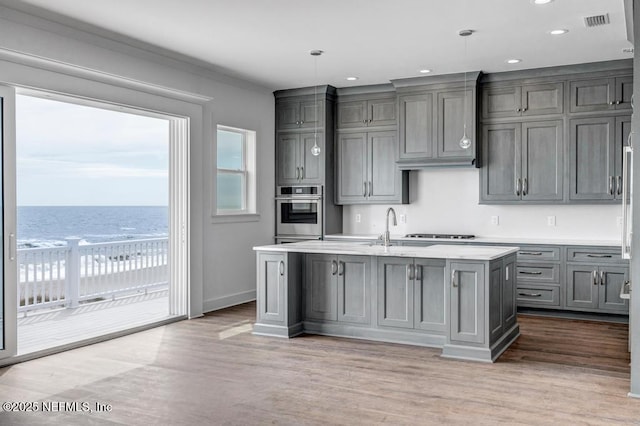 kitchen featuring visible vents, gray cabinetry, a sink, wood finished floors, and oven