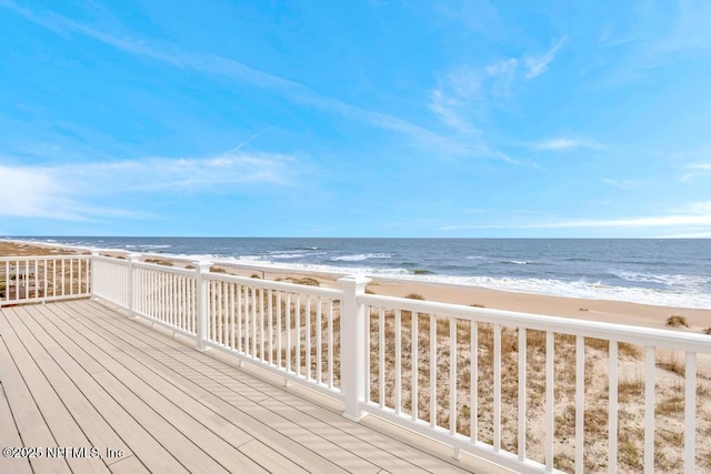 wooden terrace featuring a water view and a beach view