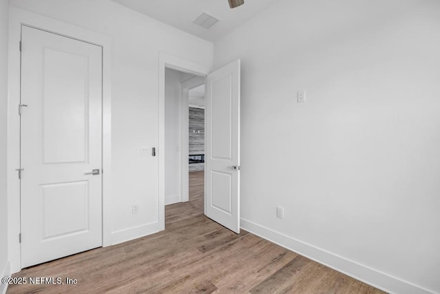 unfurnished bedroom featuring wood finished floors, visible vents, and baseboards