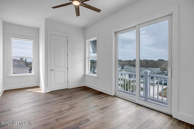 empty room with wood finished floors, a ceiling fan, and baseboards