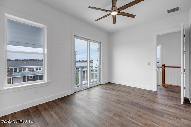 spare room with a ceiling fan, wood finished floors, visible vents, and baseboards