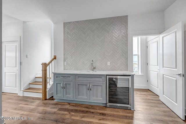 bar with wood finished floors, wine cooler, indoor wet bar, and a sink