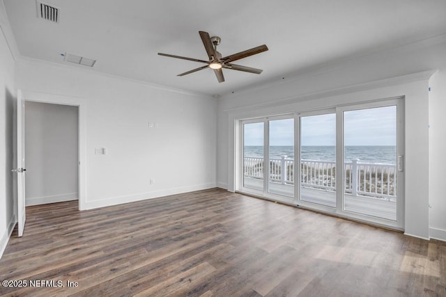 spare room featuring baseboards, visible vents, wood finished floors, a water view, and crown molding