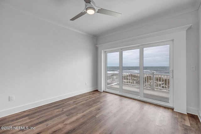 unfurnished room featuring ornamental molding, a water view, wood finished floors, and baseboards