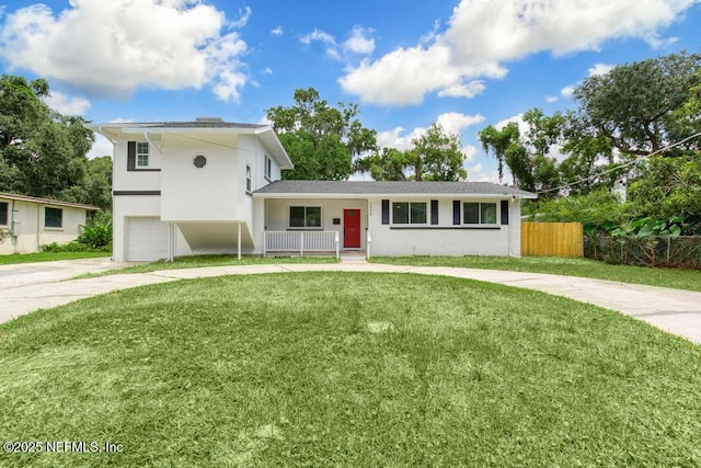 tri-level home featuring stucco siding, concrete driveway, an attached garage, fence, and a front lawn