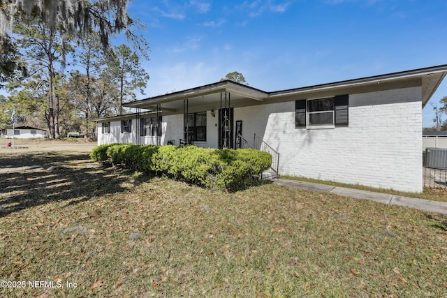 view of front of house with brick siding, central air condition unit, and a front yard