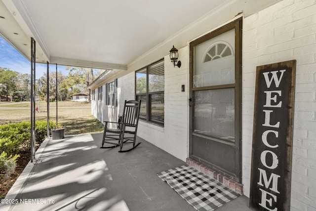 doorway to property with a porch and brick siding