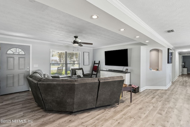 living room with visible vents, baseboards, light wood-style flooring, ornamental molding, and a textured ceiling