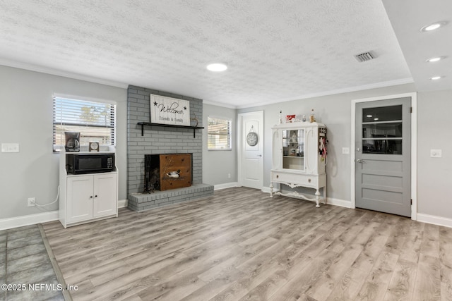 unfurnished living room featuring a healthy amount of sunlight, a fireplace, crown molding, and light wood-style floors