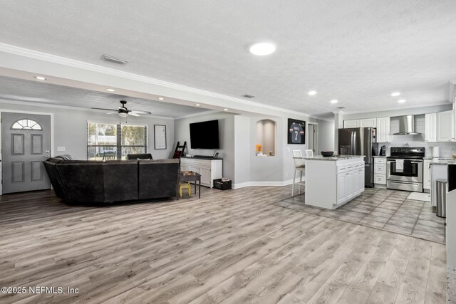 living room with visible vents, ornamental molding, recessed lighting, light wood-style floors, and a textured ceiling