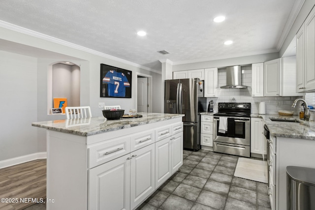 kitchen featuring visible vents, a sink, tasteful backsplash, stainless steel appliances, and wall chimney exhaust hood